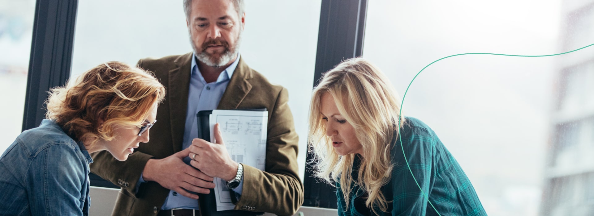 Ein Mann und zwei Frauen im Businessoutfit besprechen etwas